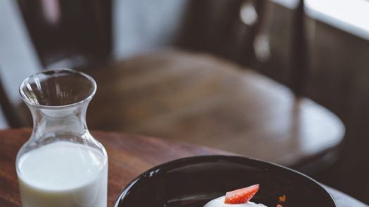 bowl of cereal with strawberries beside glass of milk on table