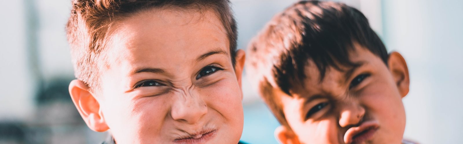 shallow focus photography of two boys doing wacky faces