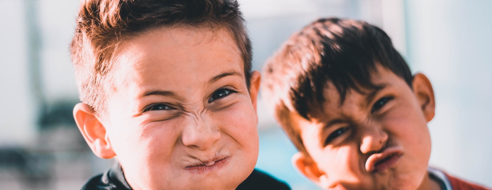 shallow focus photography of two boys doing wacky faces