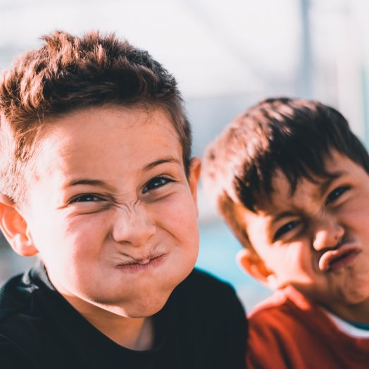 shallow focus photography of two boys doing wacky faces