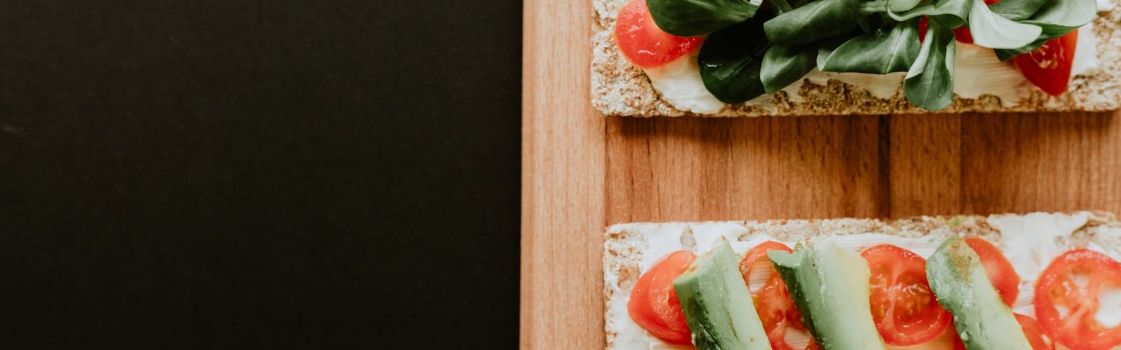 bread with vegetables, sliced tomatoes and spread filling on brown wooden board