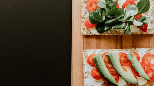 bread with vegetables, sliced tomatoes and spread filling on brown wooden board