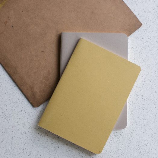 yellow and gray softbound book near brown clip board