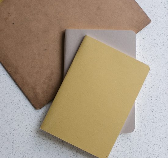 yellow and gray softbound book near brown clip board