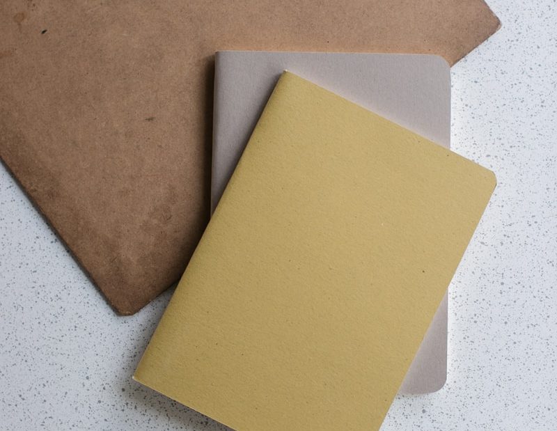 yellow and gray softbound book near brown clip board
