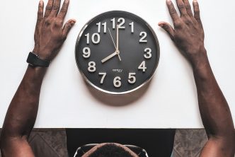 round black and white analog wall clock in front of man