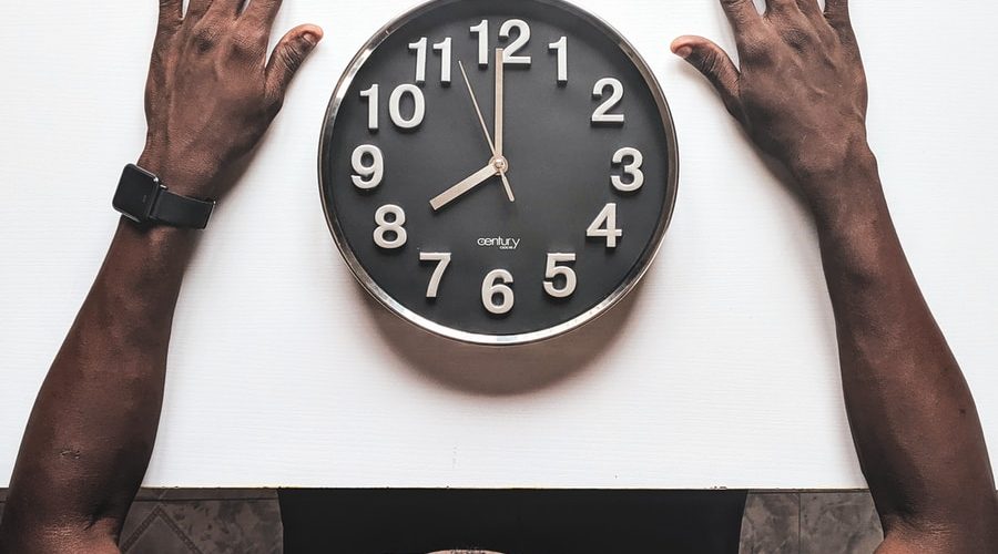 round black and white analog wall clock in front of man