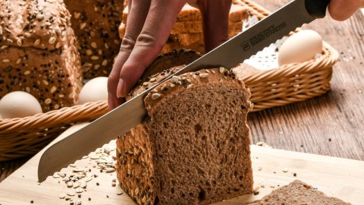 person holding knife slicing bread