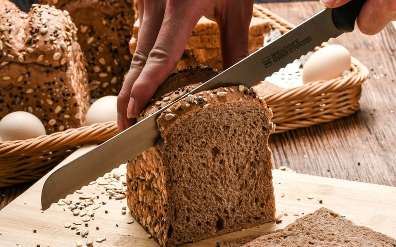 person holding knife slicing bread